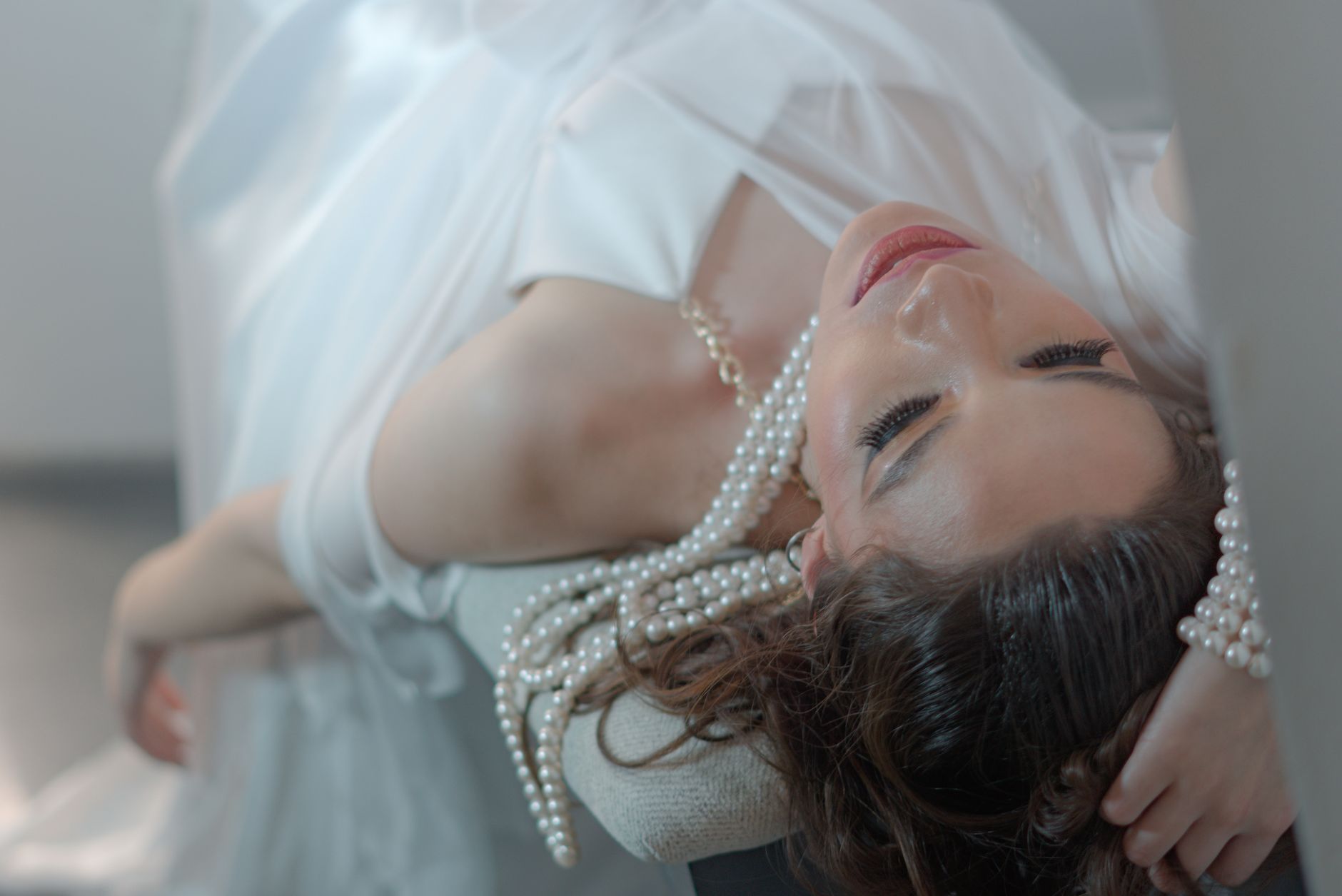 A woman in a white dress with pearl accessories reclines gracefully indoors. — Live Video Chat To Fulfill New Folks Immediate